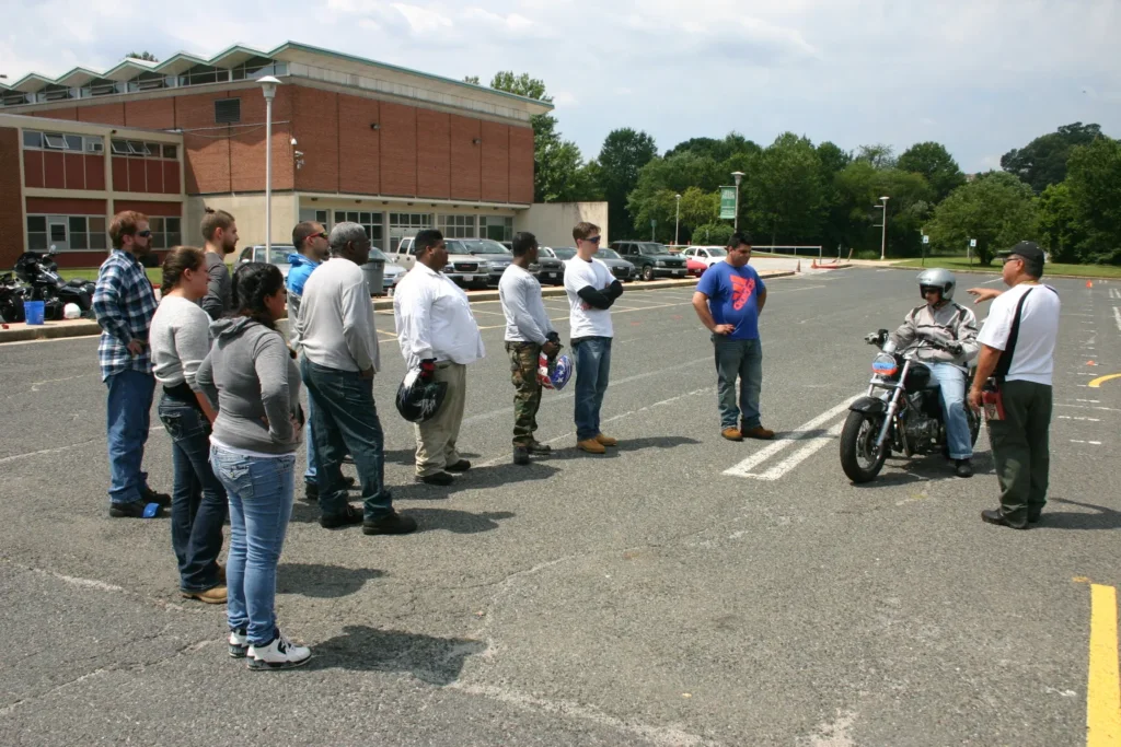 Motorcycle safety instructor teaching a group of students during an outdoor training session.